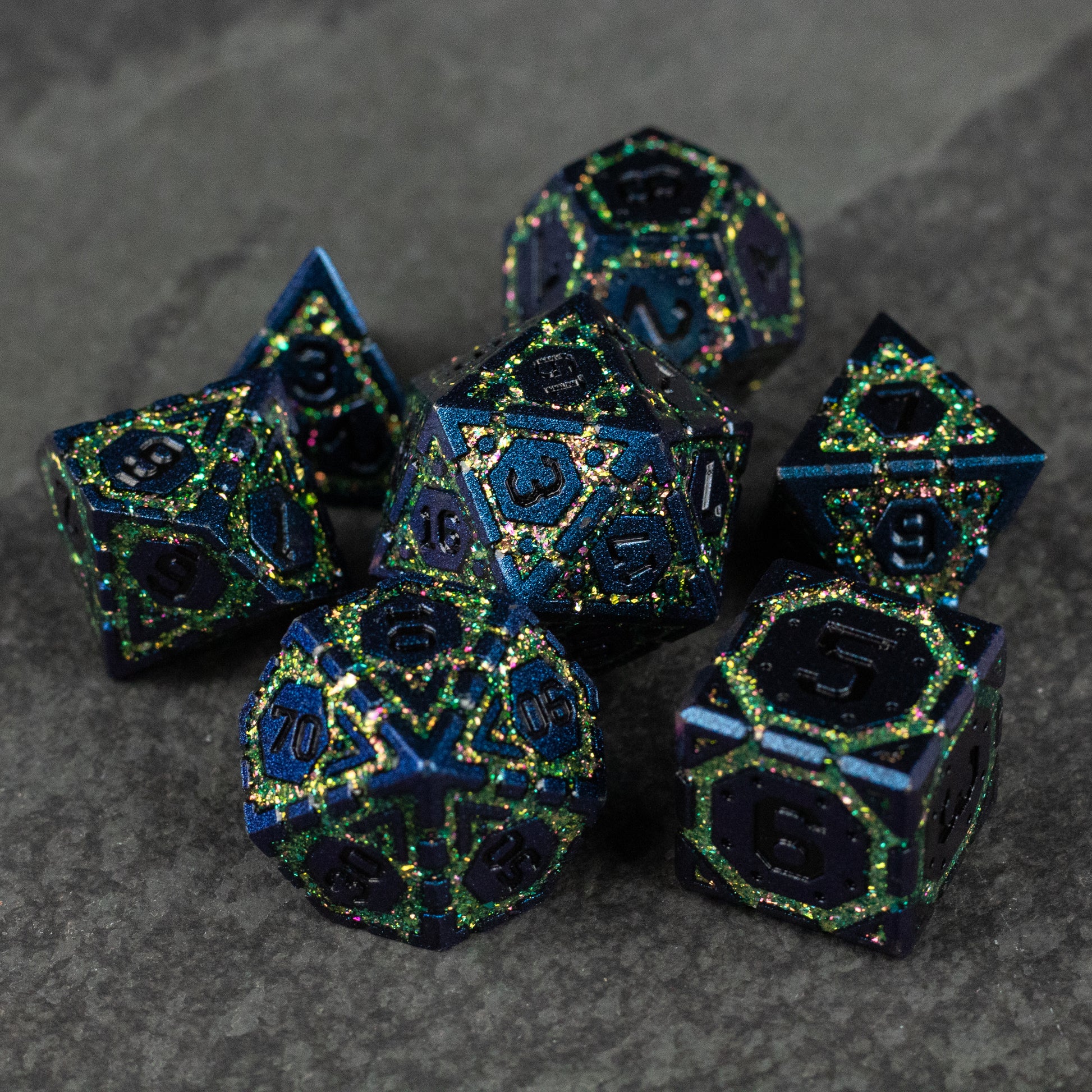Green Superior Ward Metal Dice Set - Set of seven green and black metal polyhedral dice with intricate metallic numbering and edges.
