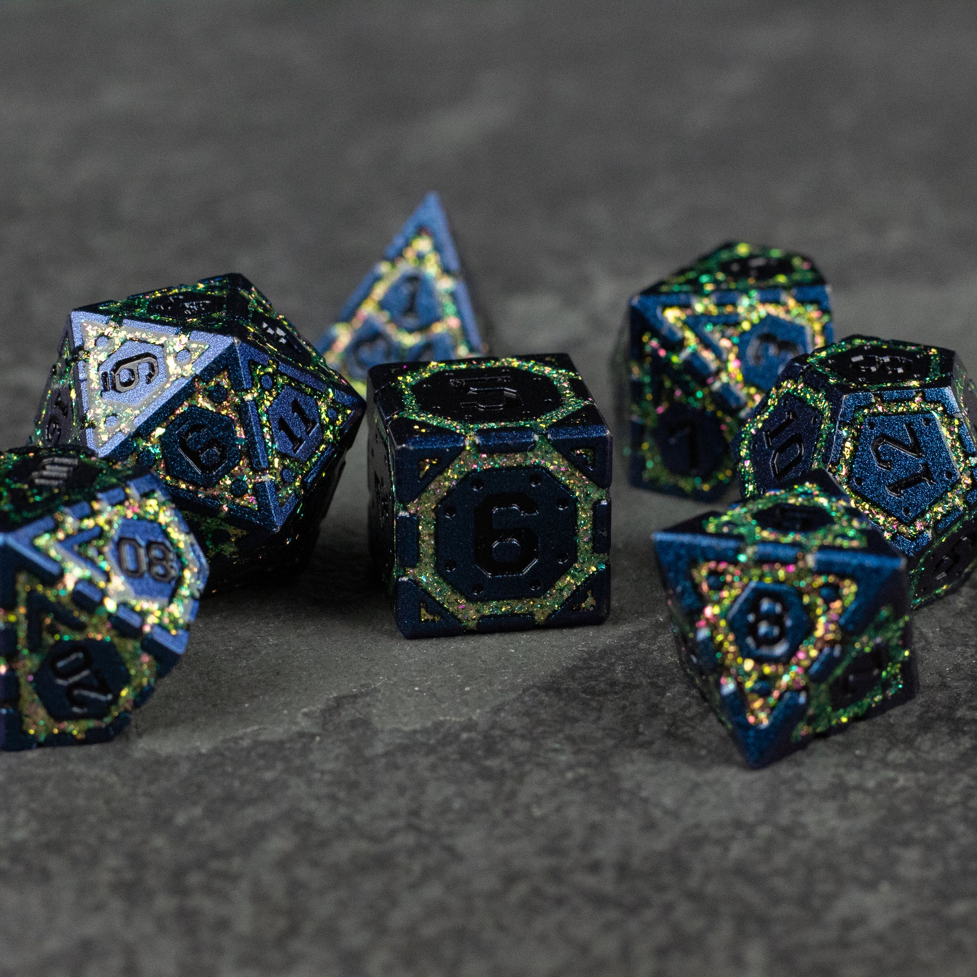 Green Superior Ward Metal Dice Set - Green metal polyhedral dice set with gold numbers and black speckled details on a gray surface.