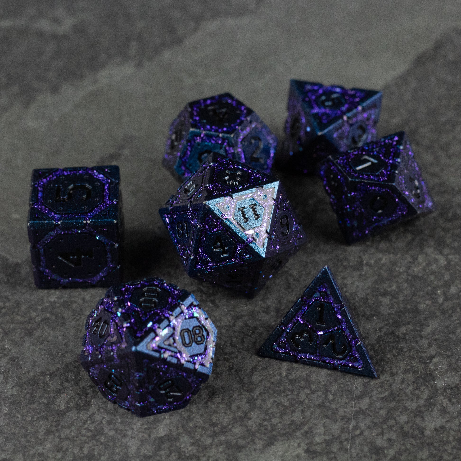 Purple Superior Ward Metal Dice Set - Set of seven metallic purple polyhedral dice with silver numbering and a glitter finish on a dark textured surface.