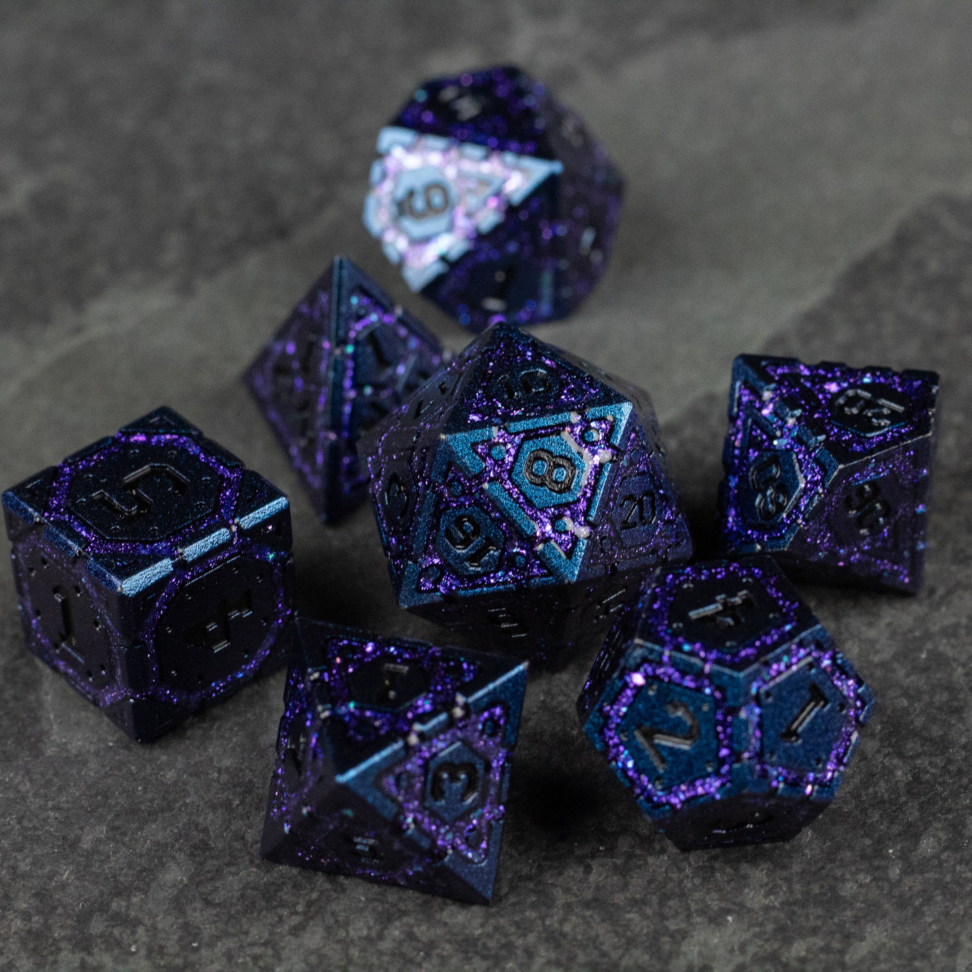 Purple Superior Ward Metal Dice Set - Set of seven purple metal dice with a shimmering speckled finish and engraved blue numbers.
