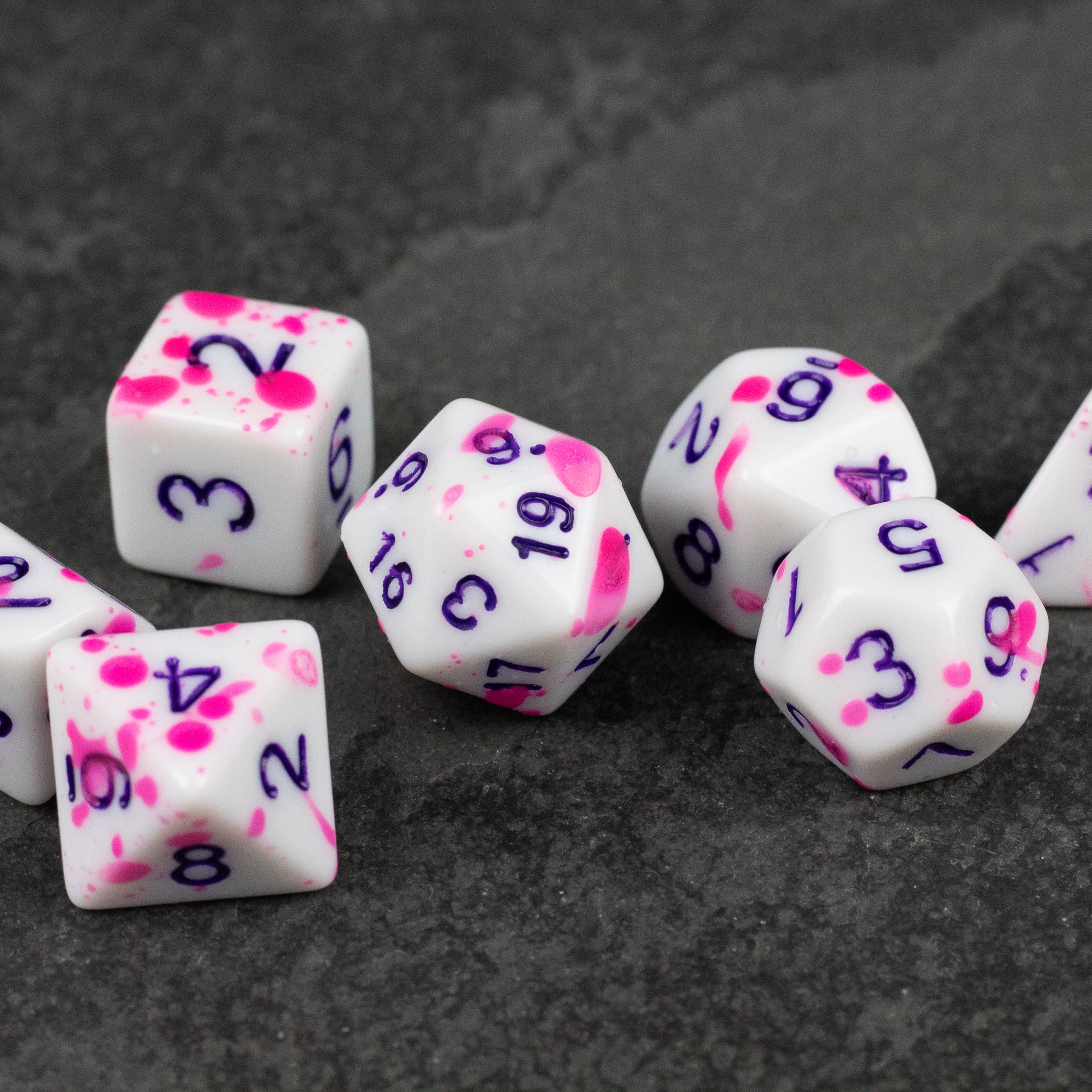 Color Change Purple Splatter Dice Set - White polyhedral dice set with purple splatter patterns and purple numbers on each face.