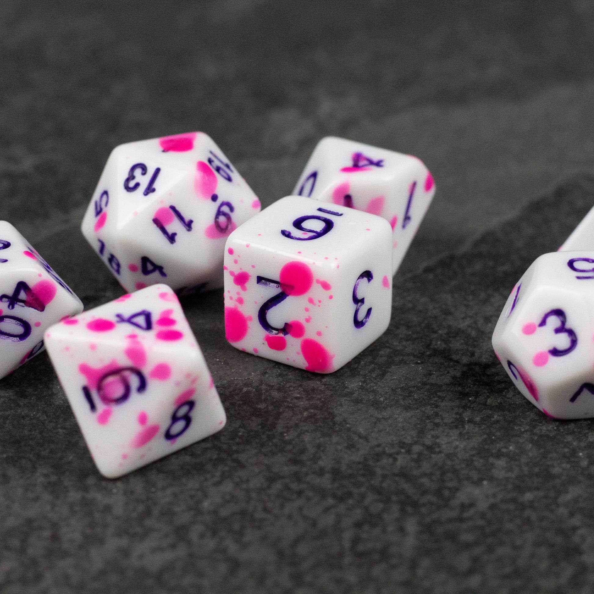 Color Change Purple Splatter Dice Set - White polyhedral dice set with purple numbering and vibrant pink splatter pattern on each die.