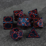 Red Superior Ward Metal Dice Set - Set of seven metal polyhedral dice in dark blue with red crackled patterns and recessed numbers for tabletop gaming.