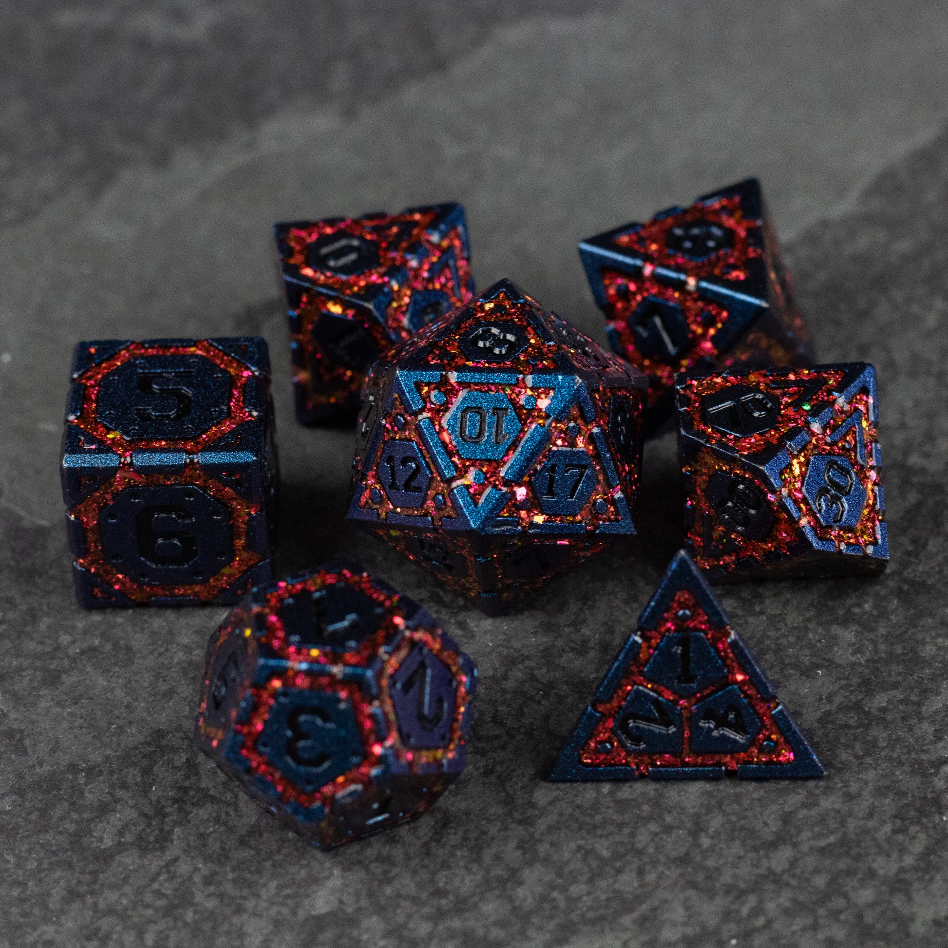 Red Superior Ward Metal Dice Set - Set of seven metal polyhedral dice in dark blue with red crackled patterns and recessed numbers for tabletop gaming.