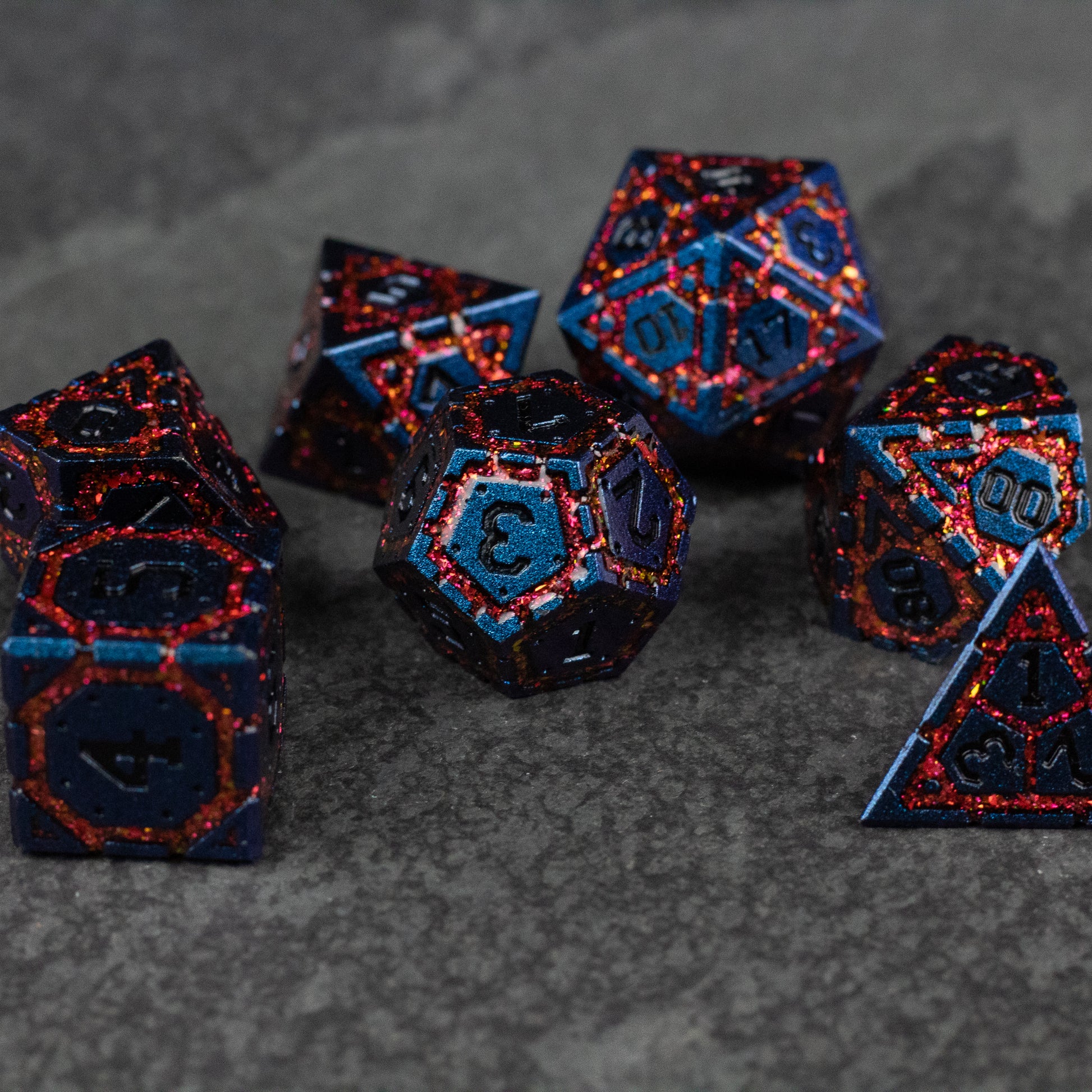 Red Superior Ward Metal Dice Set - Set of seven blue metal dice with red glitter edges, featuring various polyhedral shapes for gaming.