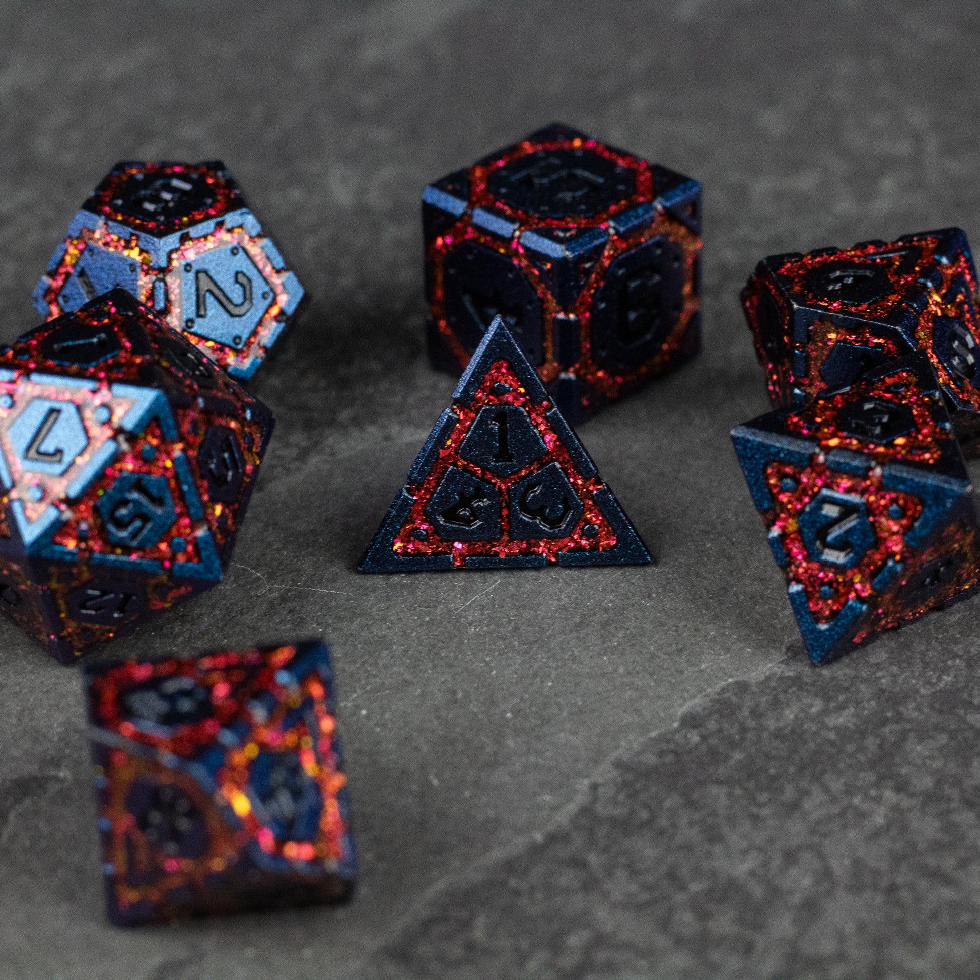 Red Superior Ward Metal Dice Set - Set of six red and black metal polyhedral dice with a sparkly finish on a dark surface.
