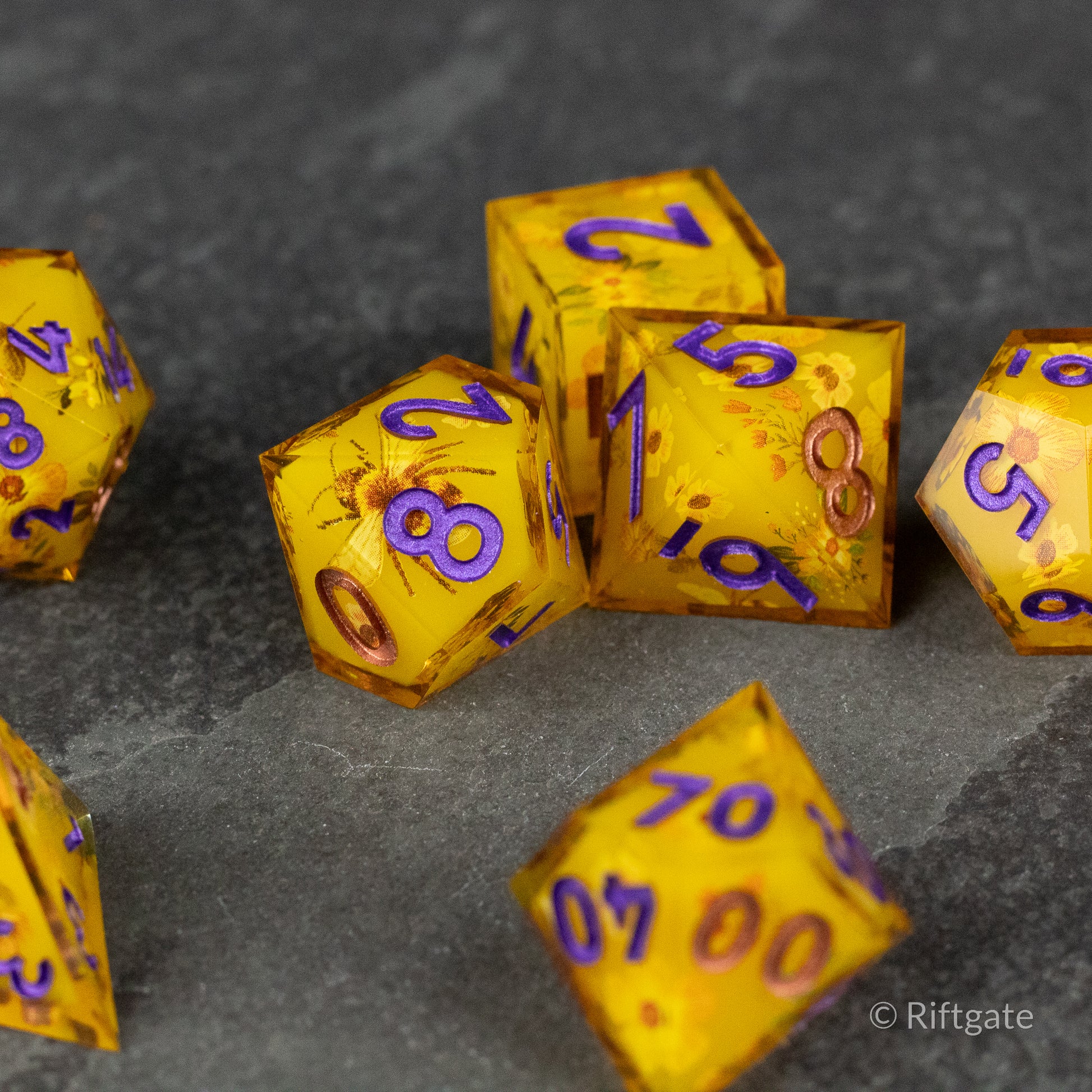 Honey Bees and Flowers Sharp Edge Dice - Golden transparent sharp edge dice with purple numbers and embedded honey bee and flower inclusions.