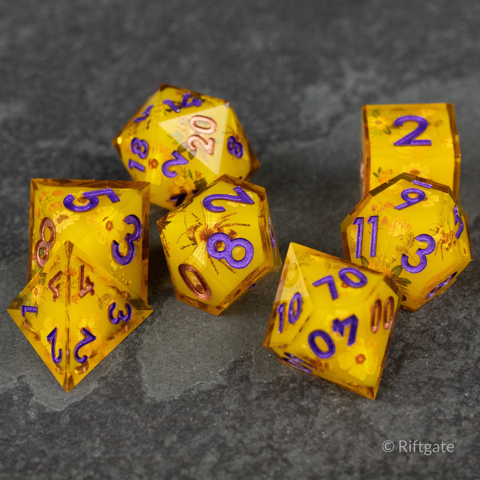 Honey Bees and Flowers Sharp Edge Dice - Set of seven yellow sharp edge polyhedral dice with purple numbers and subtle honeybee and flower designs.