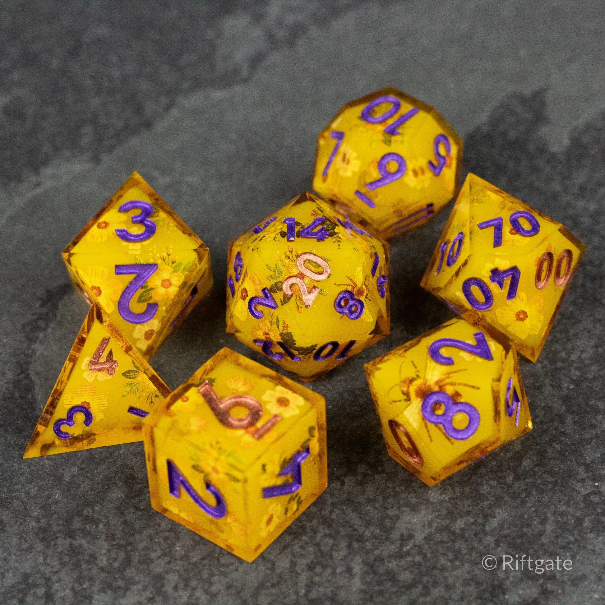 Honey Bees and Flowers Sharp Edge Dice - Seven yellow sharp edge dice with purple numbers, decorated with honey bee and flower designs on a dark surface.