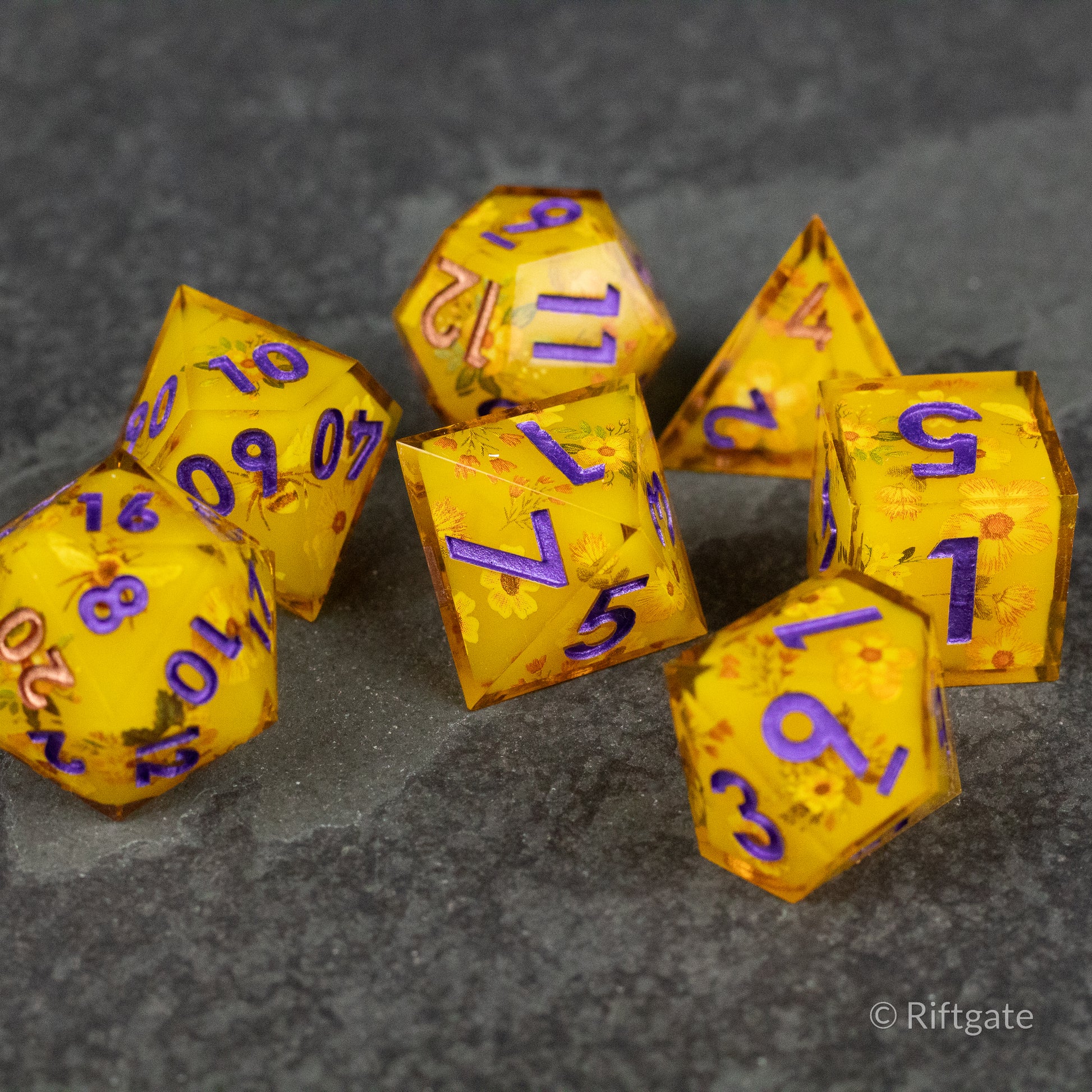 Honey Bees and Flowers Sharp Edge Dice - Set of seven yellow sharp edge dice with purple numbers and honey bee and flower patterns.