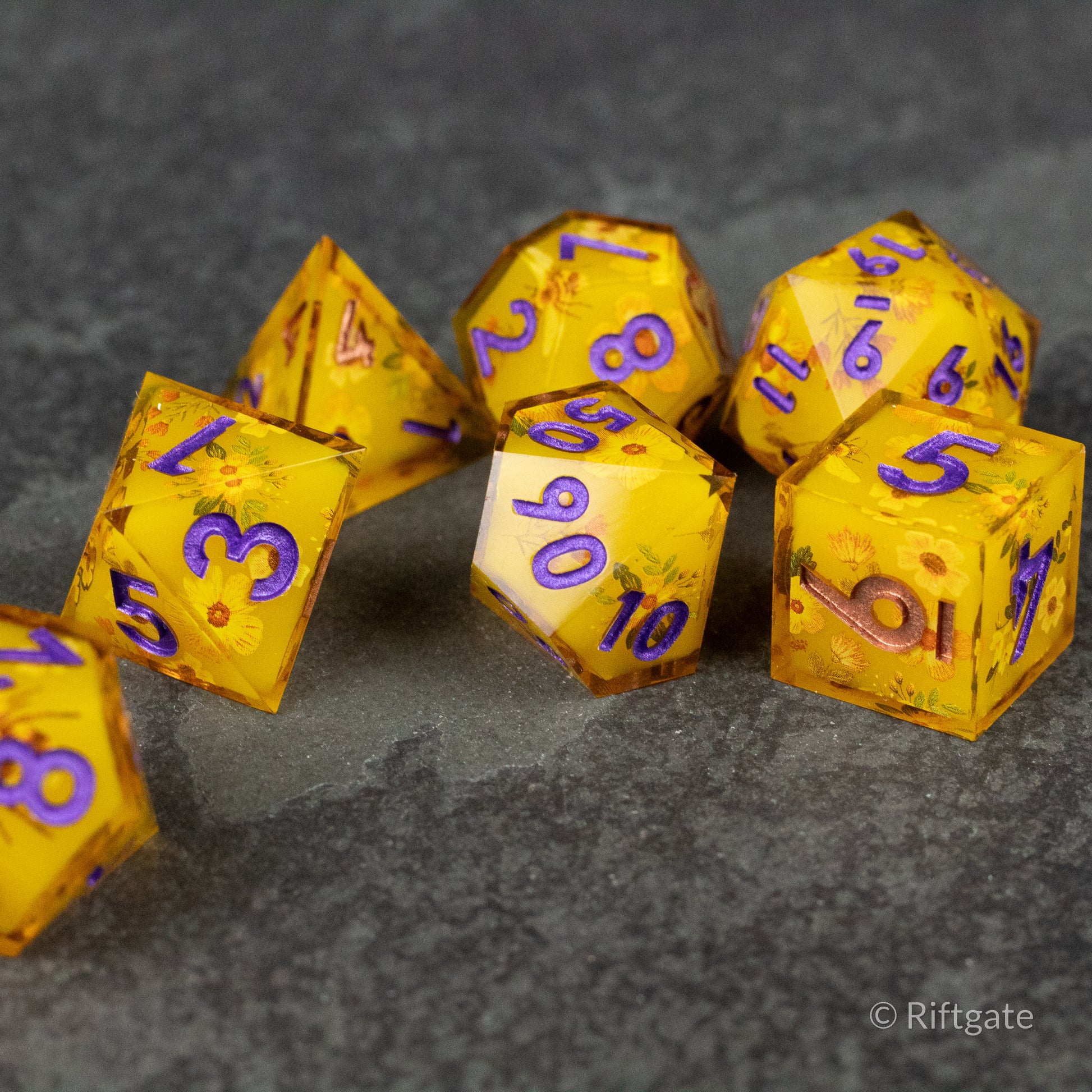 Honey Bees and Flowers Sharp Edge Dice - Set of seven yellow sharp-edged dice with purple numbers, featuring honey bee and flower patterns inside translucent resin.