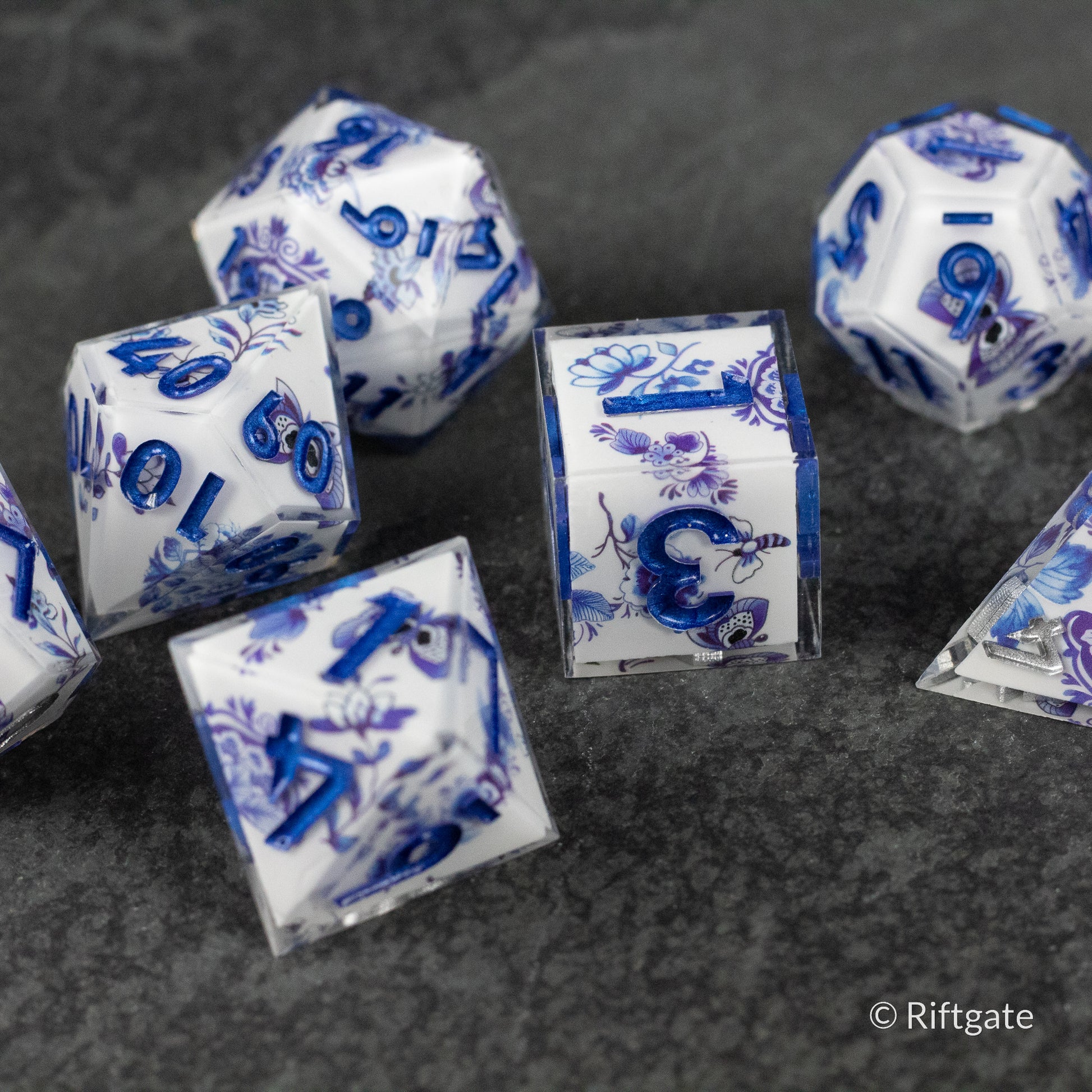 Moonlight Garden Dice Set - White translucent polyhedral dice set with intricate blue floral and leaf patterns, glossy finish.