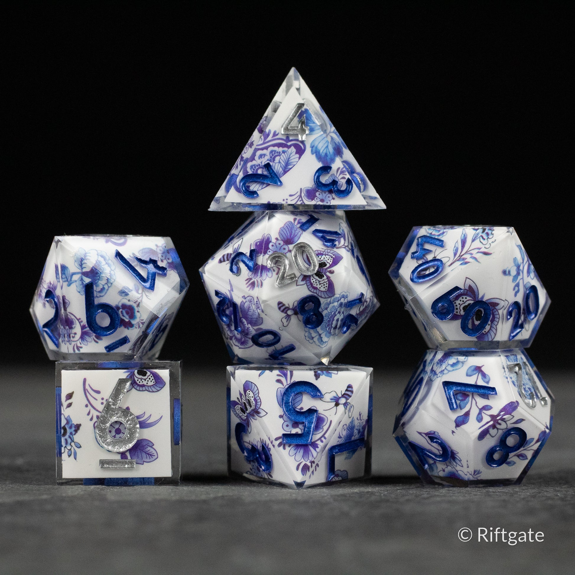 Moonlight Garden Dice Set - White polyhedral dice set with intricate blue floral and moonlight-themed designs and bold blue numbers.
