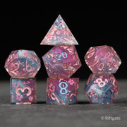 Twilight Blossoms Dice Set - Set of seven sharp-edged polyhedral dice with pink and blue marbled pattern and metallic rose gold numbers.