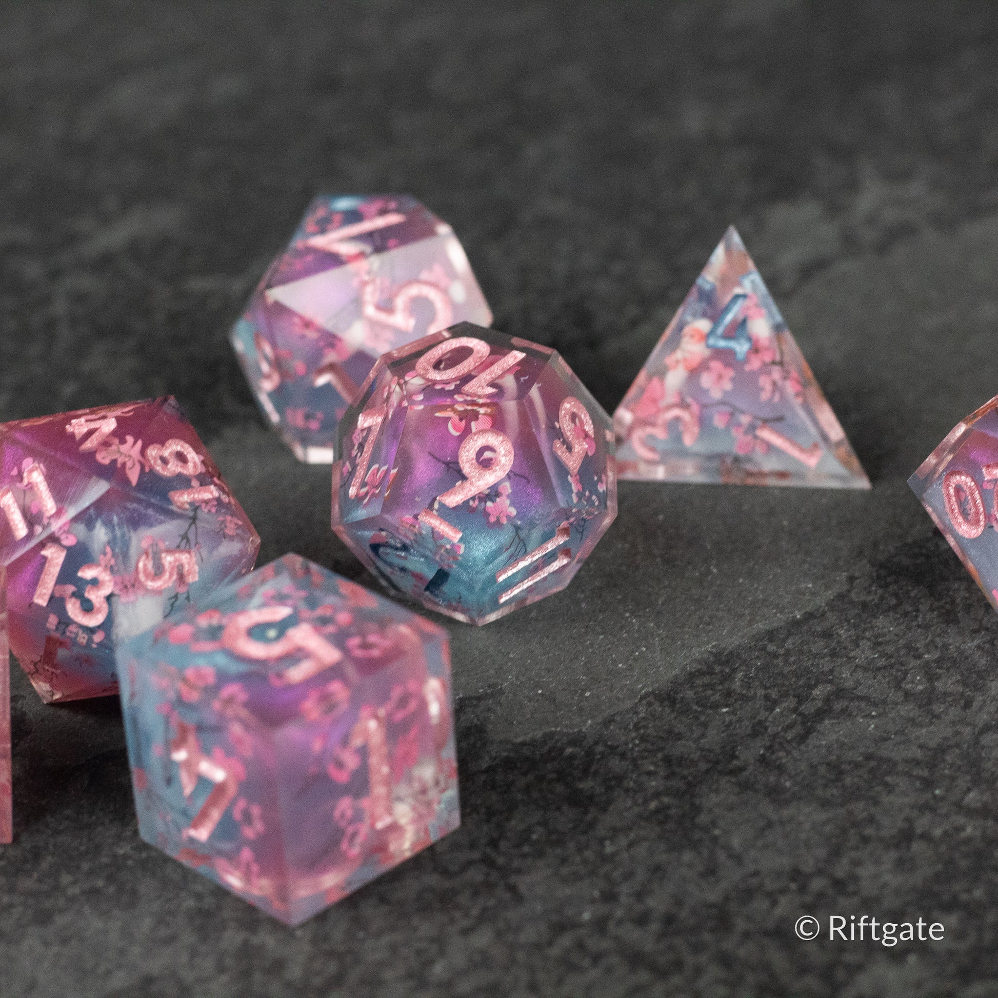 Twilight Blossoms Dice Set - Translucent purple and blue sharp-edged polyhedral dice with white numbering and floral inclusions.