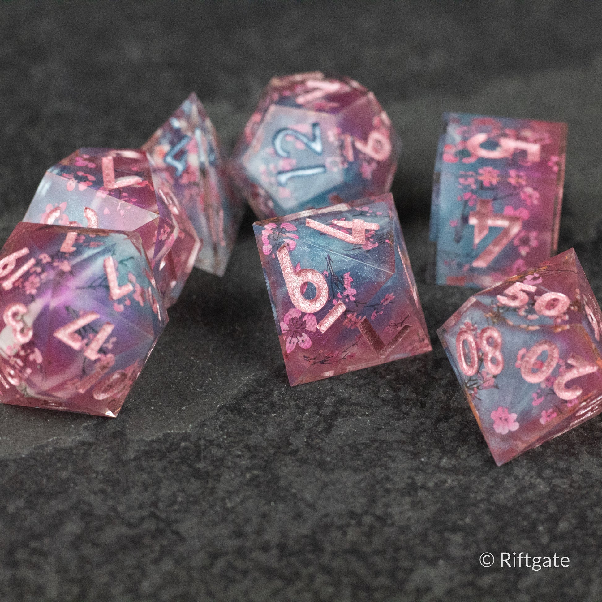 Twilight Blossoms Dice Set - Translucent pink polyhedral dice set with sharp edges and white numbering, featuring embedded floral patterns.