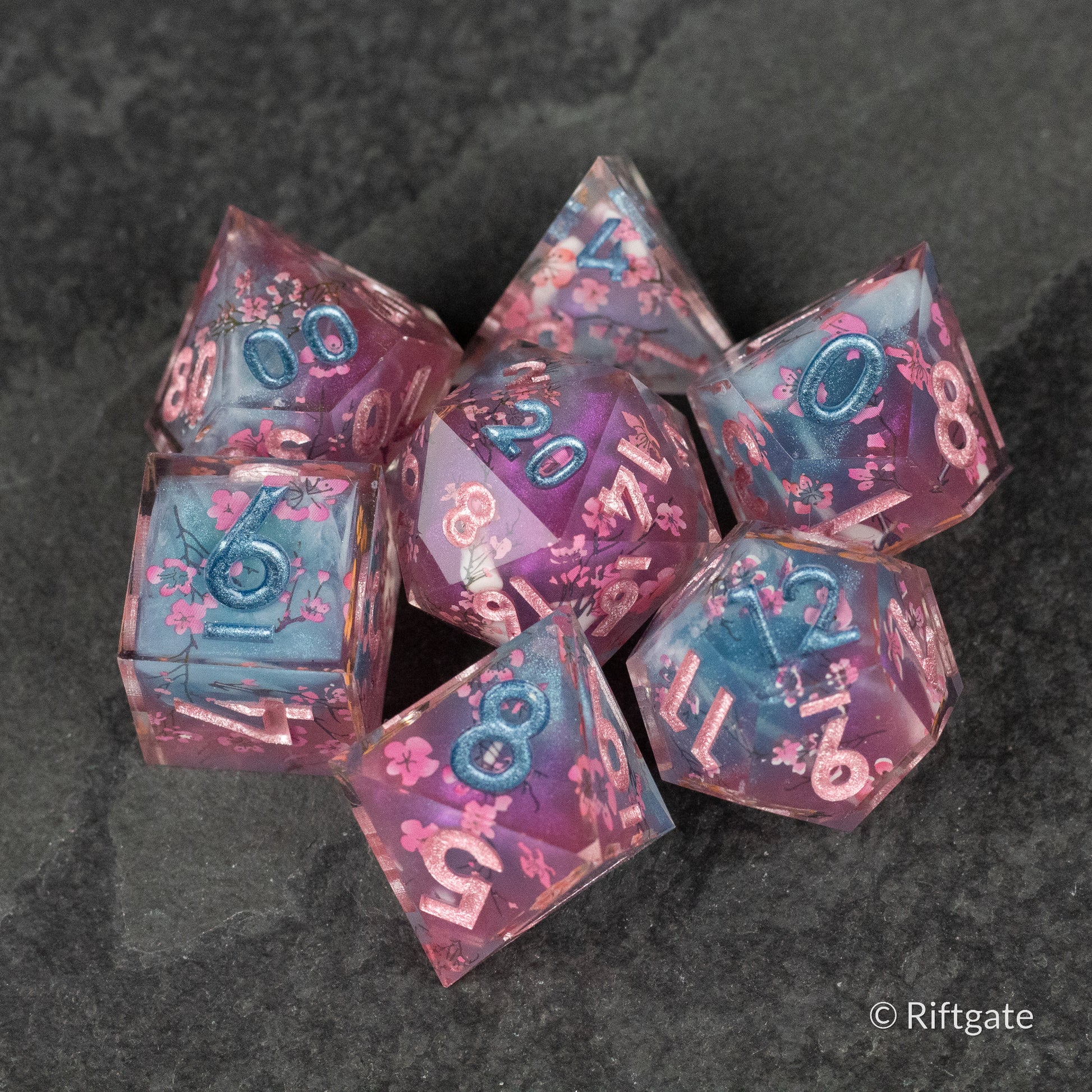 Twilight Blossoms Dice Set - Purple and pink translucent sharp edge dice set with intricate floral inclusions and white numbering.