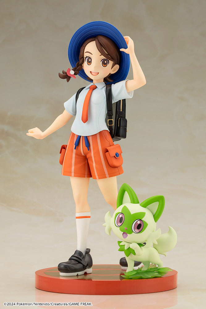 Pokemon Juliana with Sprigatito ARTFX J STATUE - Juliana figurine in blue hat, white shirt, orange shorts with black backpack beside green Sprigatito statue on round base.