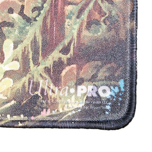 Ultra Pro Holofoil Playmat for Magic: The Gathering: The Lost Caverns of Ixalan : Ruins Symbol - Close-up of holographic Ultra Pro playmat corner with stitched black edging and multicolored forest-themed design.