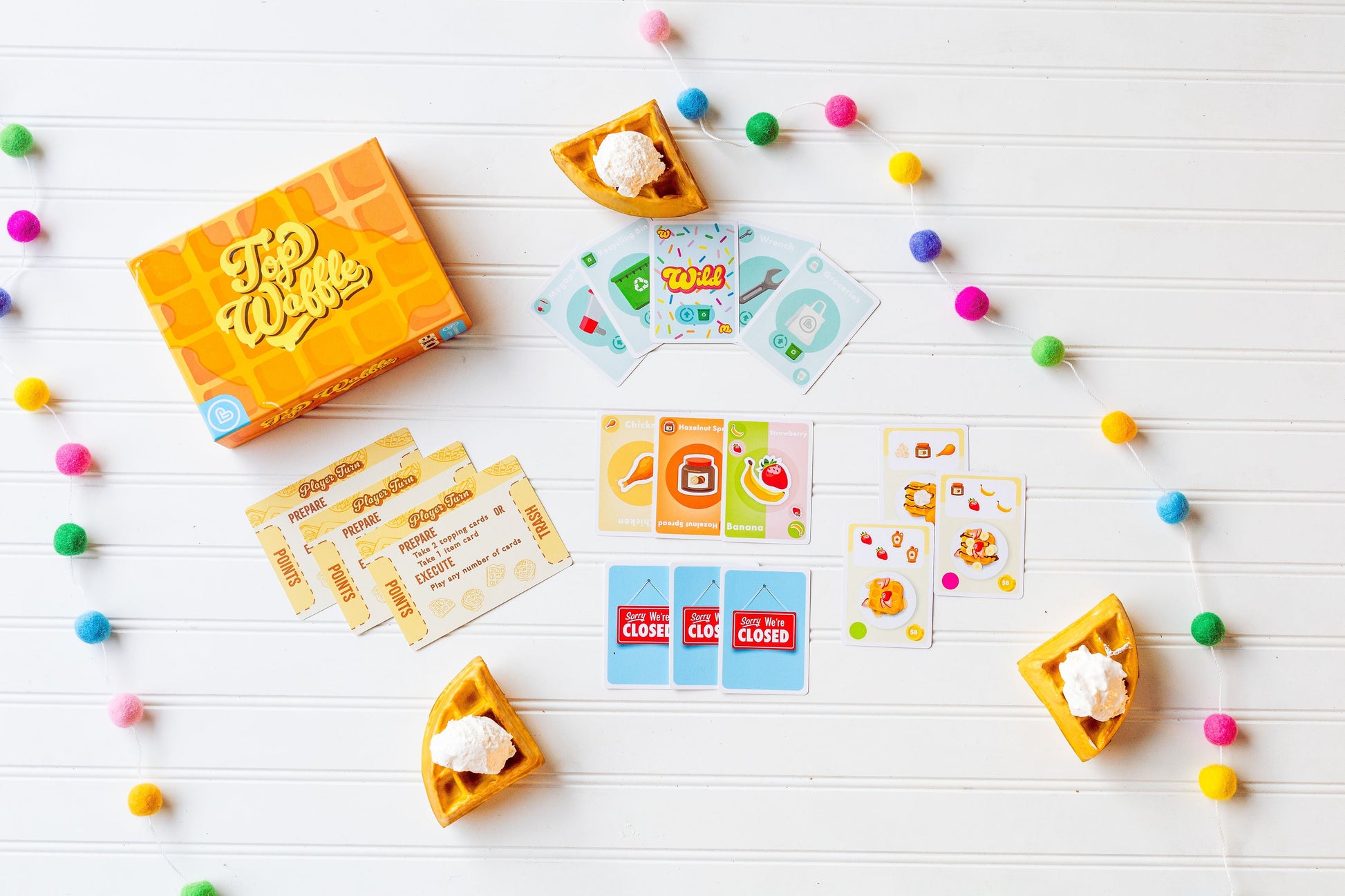 Top Waffle - Orange card game box with "Top Waffle" branding, colorful cards, and waffle-shaped card holders on white background.