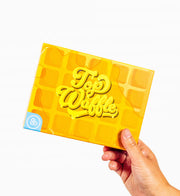 Top Waffle - Yellow waffle-patterned card game box with embossed "Top Waffle" text held by a hand.