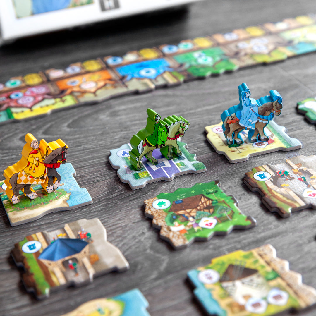 Middle-Ages - Colorful miniature medieval figures and detailed hexagonal game tiles arranged on a wooden surface.