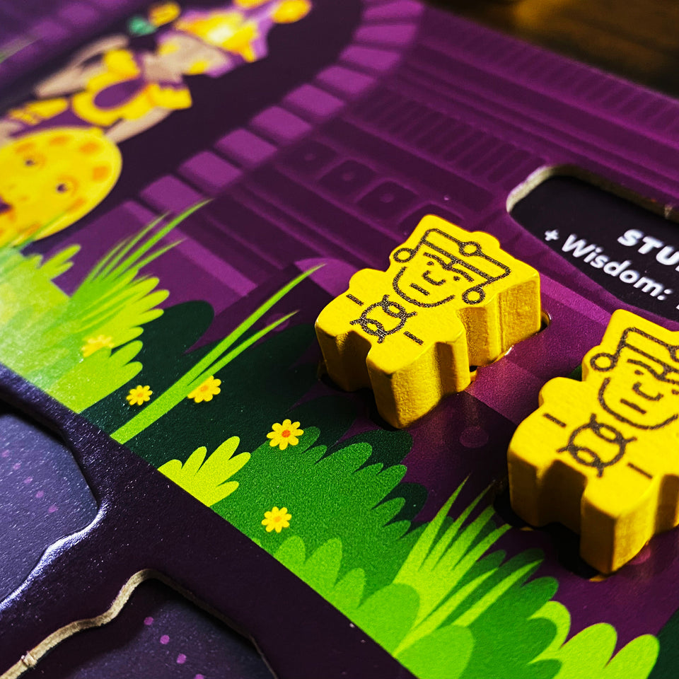 Oros Collector's Edition - Yellow wooden game tokens shaped like stylized owls on a purple board with green grass and yellow flower illustrations.
