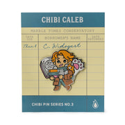 Critical Role Chibi Pin - Caleb Widowgast - Chibi-style enamel pin of a character with orange hair, brown robe, and mechanical gauntlet holding a rapier, set on library