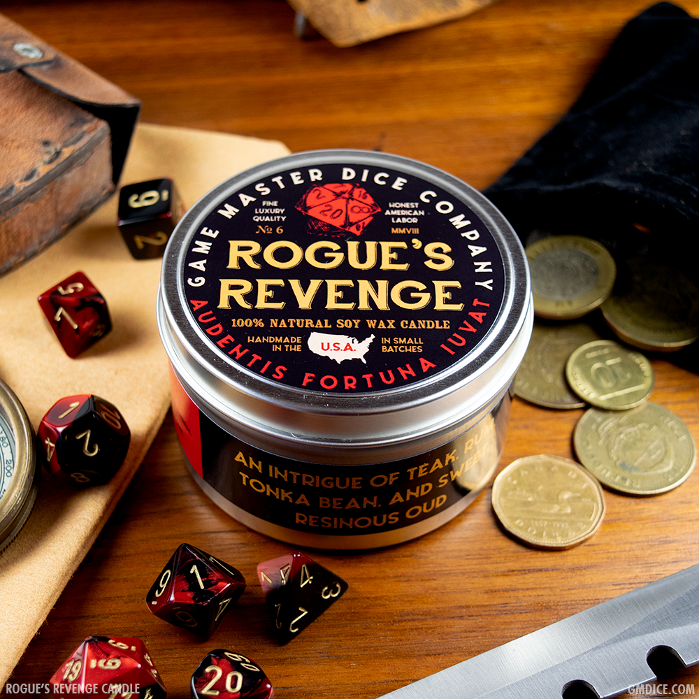Rogue's Revenge Gaming Candle - Round metal tin candle labeled Rogue's Revenge with black, red, and beige design and fantasy dice on wooden surface.