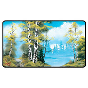 Playmat: Stitched Edge: Bob Ross: Lakeside Path - Rectangular playmat with stitched black edges featuring a vibrant lakeside scene of birch trees and yellow foliage under a.