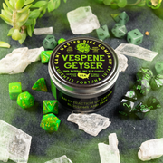 Vespene Geyser Gaming Candle - Round black tin candle with a bright green label reading Vespene Geyser, surrounded by green polyhedral dice and clear.
