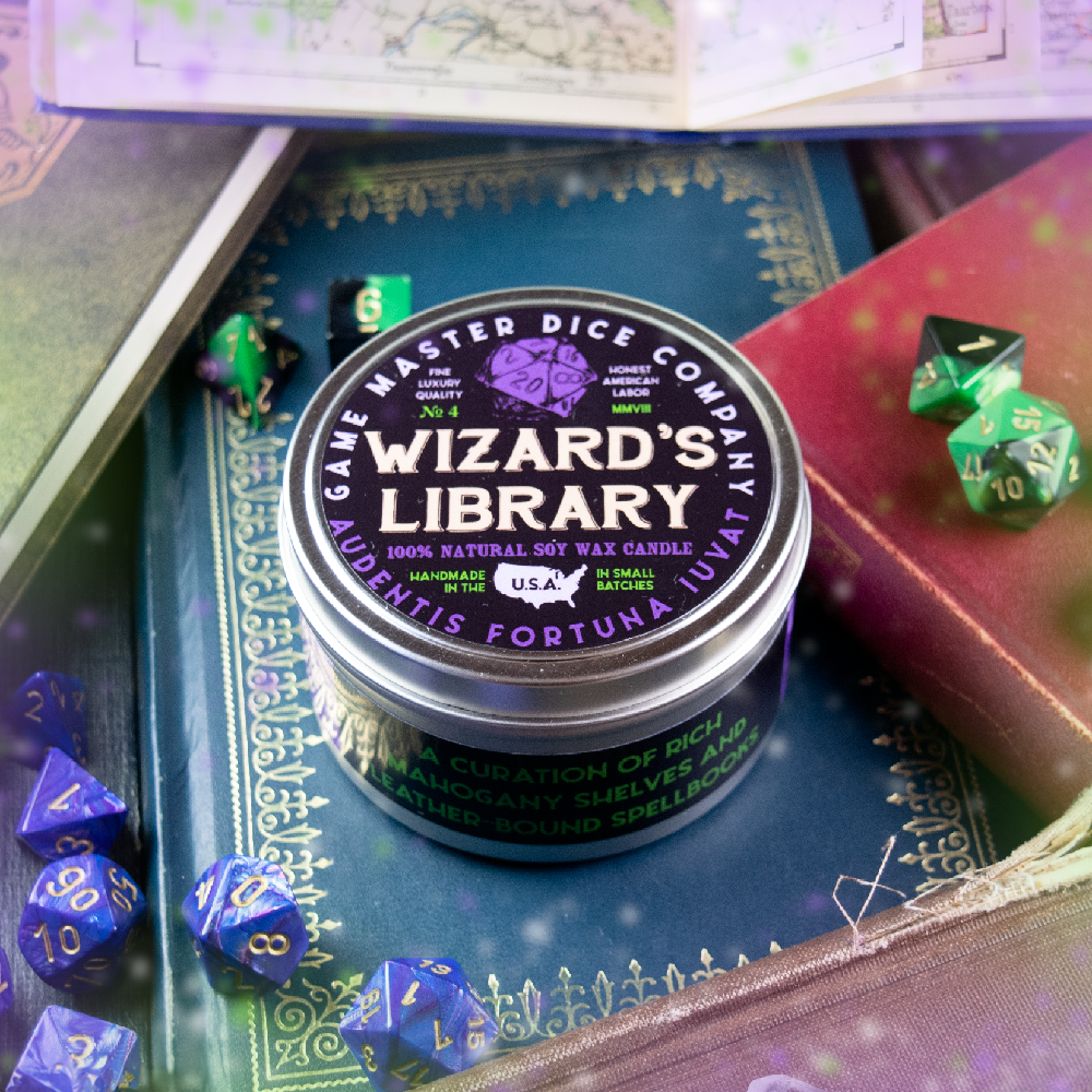 Wizard's Library Gaming Candle - Round metal tin candle labeled "Wizard's Library" with dark purple and black design, surrounded by colorful polyhedral dice.