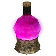 Enhance: Tabletop Potion Light: Purple - Purple glowing potion-shaped tabletop light with faceted glass and ornate bronze base.