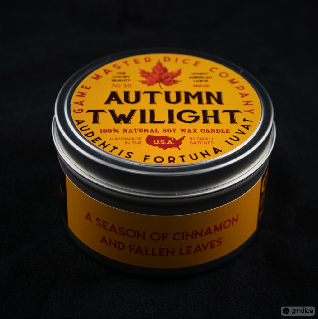 Autumn Twilight Gaming Candle - Round metal tin candle with bright orange label featuring a maple leaf and black text, scented with cinnamon and fallen.