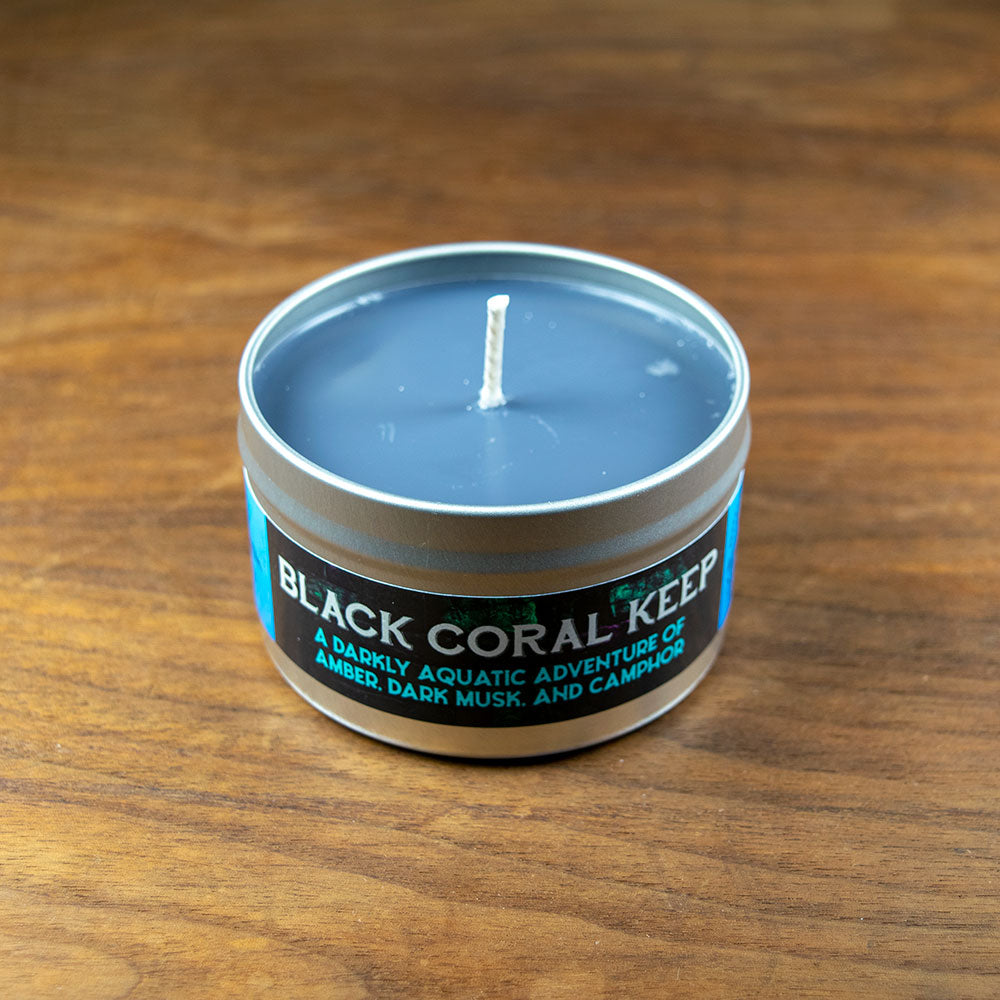 Black Coral Keep Candle - Small round metal tin candle with deep gray wax and a centered white wick, labeled Black Coral Keep.