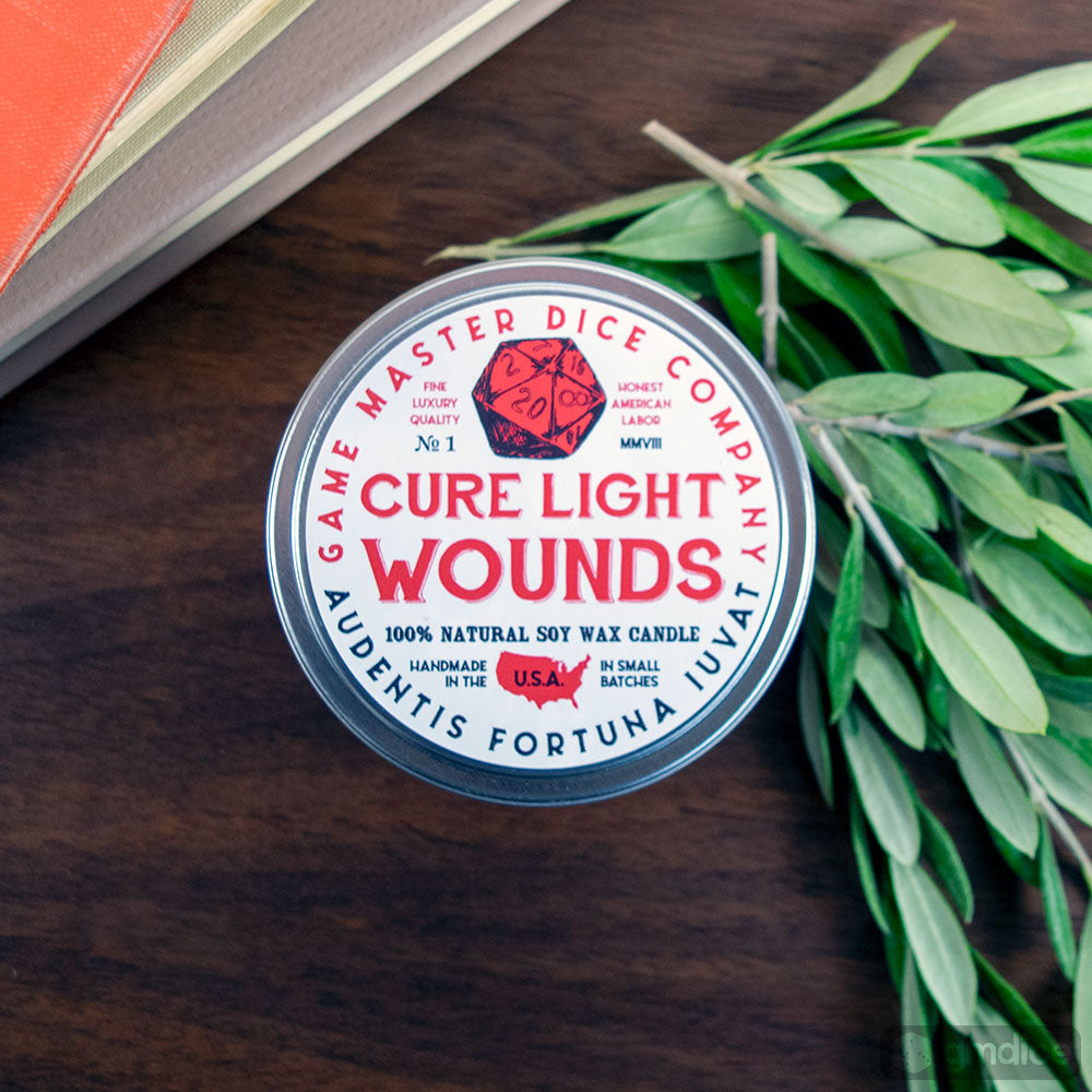 Cure Wounds Gaming Candle - Round tin candle with white label reading Cure Light Wounds, decorated with red heart and blue text, surrounded by green.