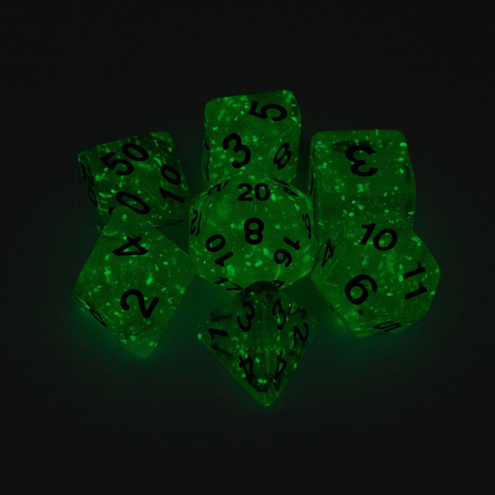 Sea of Stars - White - Glow-in-the-dark Dice Set - Green glow-in-the-dark seven-piece polyhedral dice set with black numbers, glittery finish.