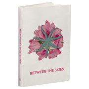 Between the Skies: Collected Edition Hardcover - Hardcover book with white cover featuring pink flower with green starfish overlay and pink title text Between the Skies.