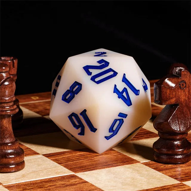 Giant Bouncy D20 - UV Color Change Blue - Large white 20-sided die with bold blue numbers on a wooden chessboard with chess pieces nearby.