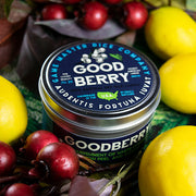 Goodberry Gaming Candle - Round metal tin candle with navy blue label featuring white lettering and green berry graphics, surrounded by cherries and.