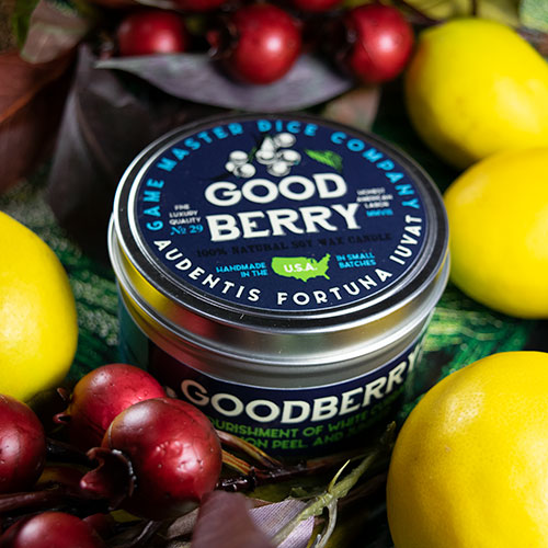 Goodberry Gaming Candle - Round metal tin candle with navy blue label featuring white lettering and green berry graphics, surrounded by cherries and.