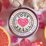 Love Spell Gaming Candle - Round white tin candle with a pink heart design and black text reading Love Spell Gaming Candle.