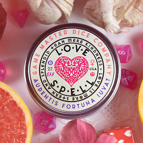Love Spell Gaming Candle - Round white tin candle with a pink heart design and black text reading Love Spell Gaming Candle.