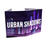 Urban Shadows MC Screen & Campaign Notepad - Folded gaming screen with purple city skyline artwork and bold white "Urban Shadows" text across the front panel.