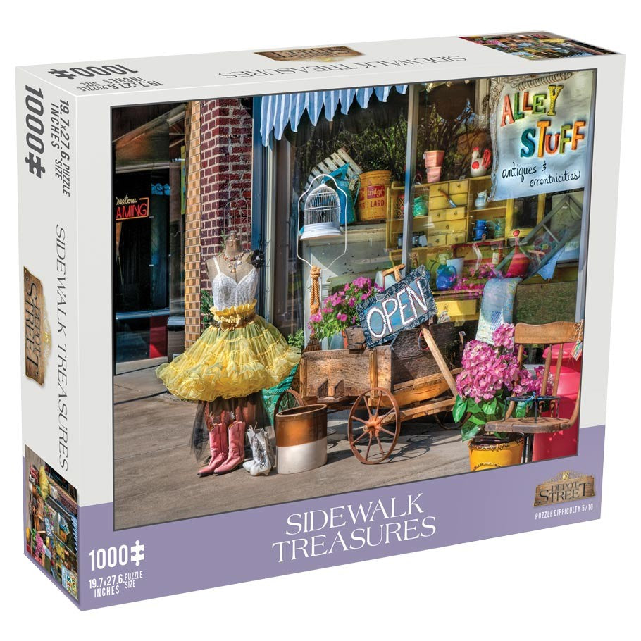 Sidewalk Treasures 1000 Piece Puzzle - 1000-piece puzzle box featuring a colorful, detailed storefront scene with mannequins, flowers, potted plants, and a rustic.