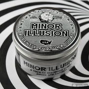 Minor Illusion Gaming Candle - Round silver tin candle with black and white label reading Minor Illusion featuring dice and decorative text.