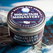 Mountain Monastery Gaming Candle - Round metal tin candle with dark purple label featuring white text and mountain graphics.