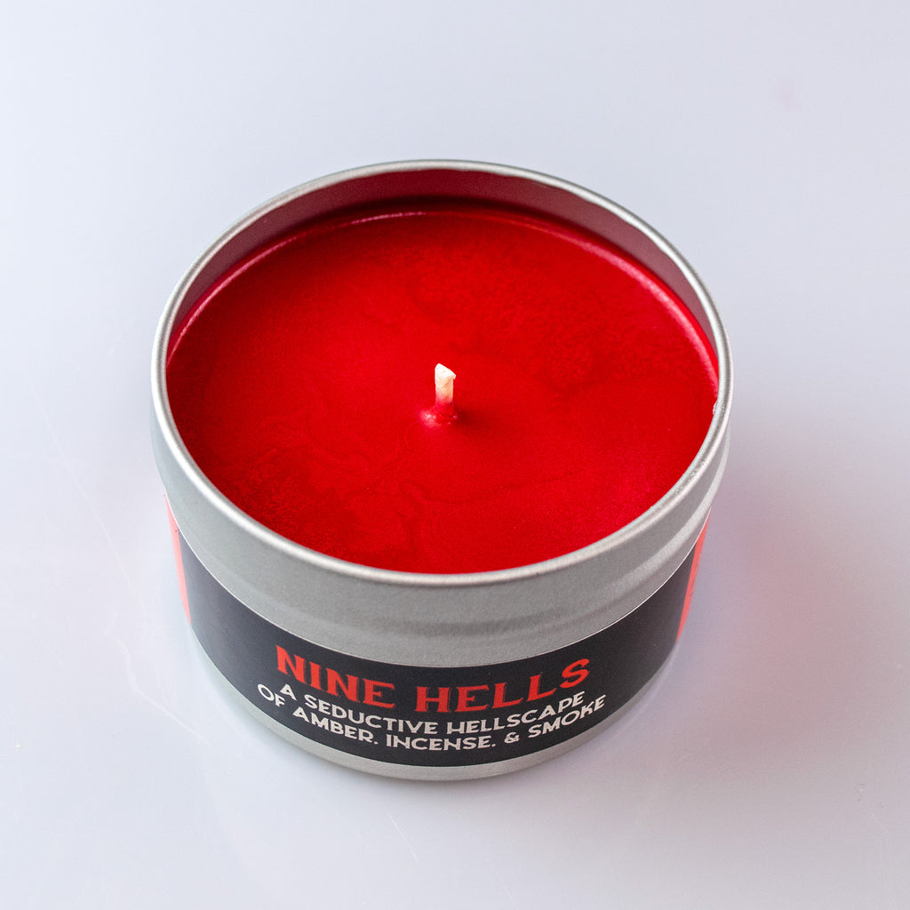 Nine Hells Gaming Candle - Red wax candle in a round black tin with silver lid, labeled Nine Hells Gaming Candle.