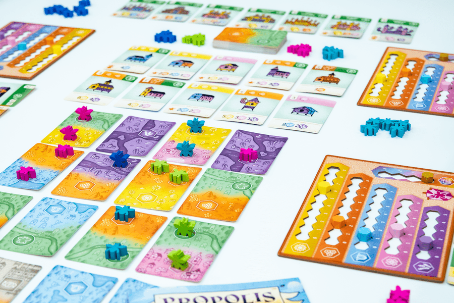 Propolis - Colorful rectangular game cards arranged in a grid with small, bright blue, purple, and green bee-shaped tokens on them,.