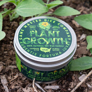 Plant Growth Gaming Candle - Small round metal tin candle with green and yellow label featuring botanical illustrations and text "Grow It" on soil.